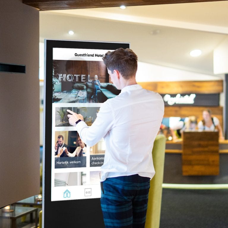 Een man die de touchscreen-kiosk als digitaal infopoint naast de receptie gebruikt
