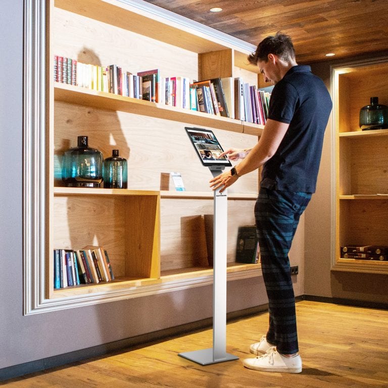 Ein Gast nutzt die Digitale Gästemappe auf einem stationären Tablet in der Hotellobby